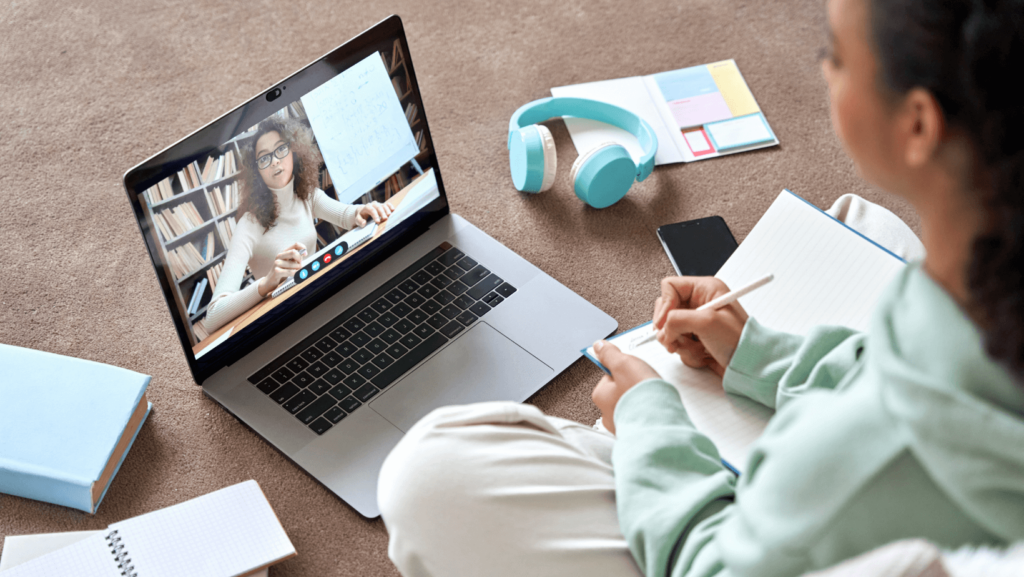 Girl on the floor with book attendign an online lesson