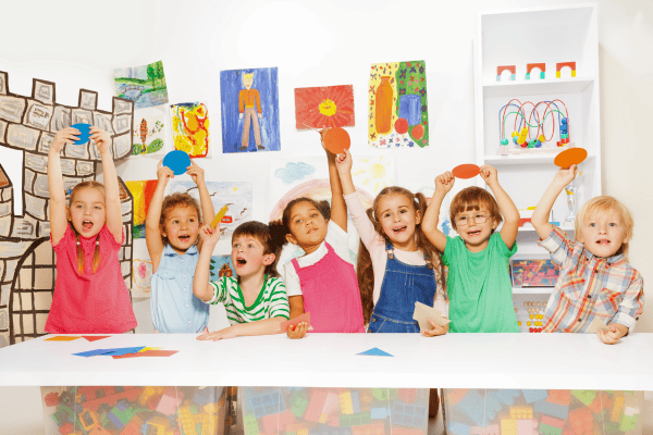 Kids with different nationalities on a classroom setting happily doing a speaking activities together.