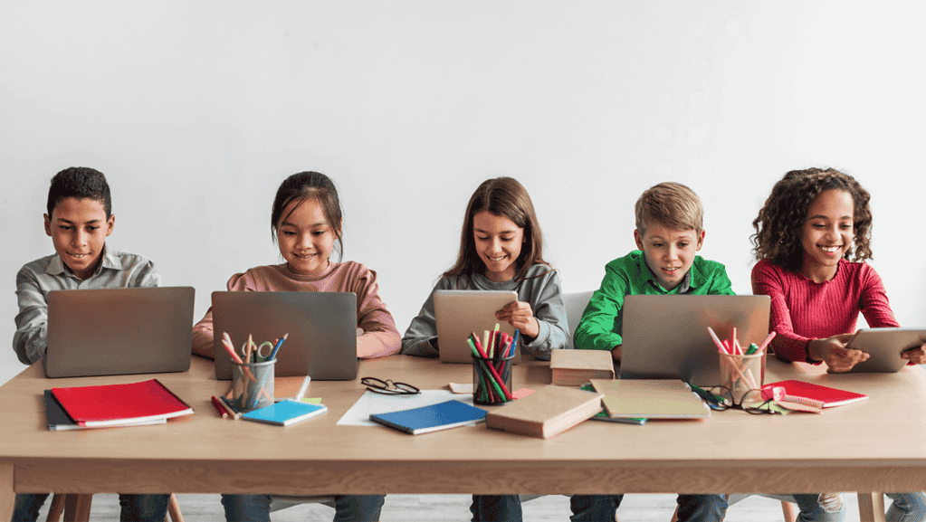 5 kids in different nationalities reading with their tablet and laptop. Doing speaking activities together for their ESL Games.