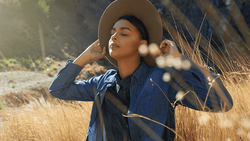 A girl in the middle of fields listening to the sounds of nature wth eyes closed